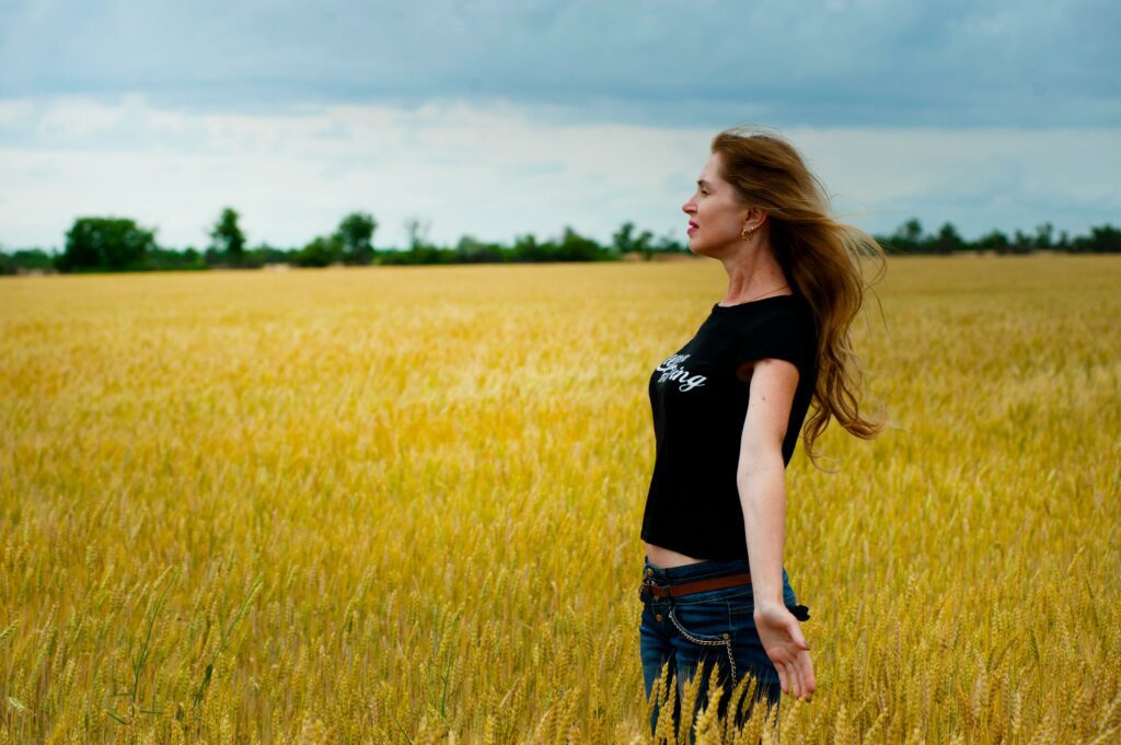 joyful woman standing in wheat field